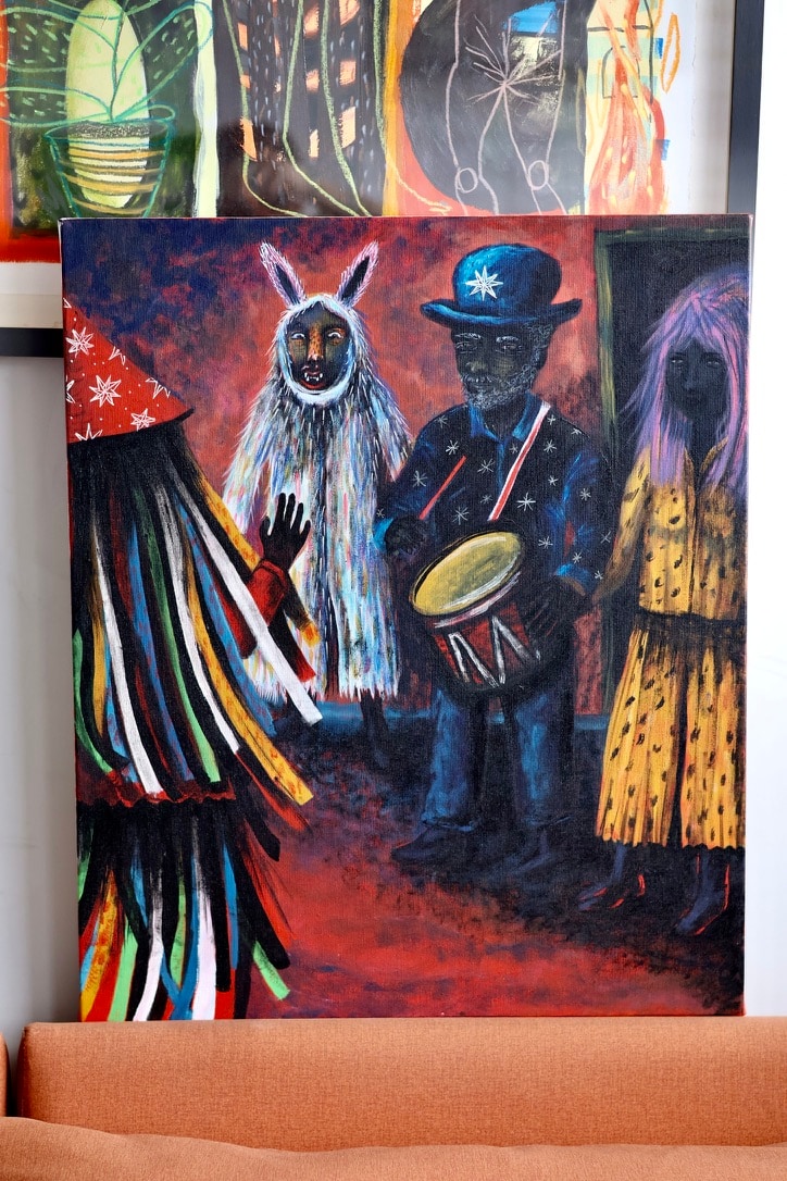 Figuras de um cortejo com máscaras, roupas coloridas e tambor